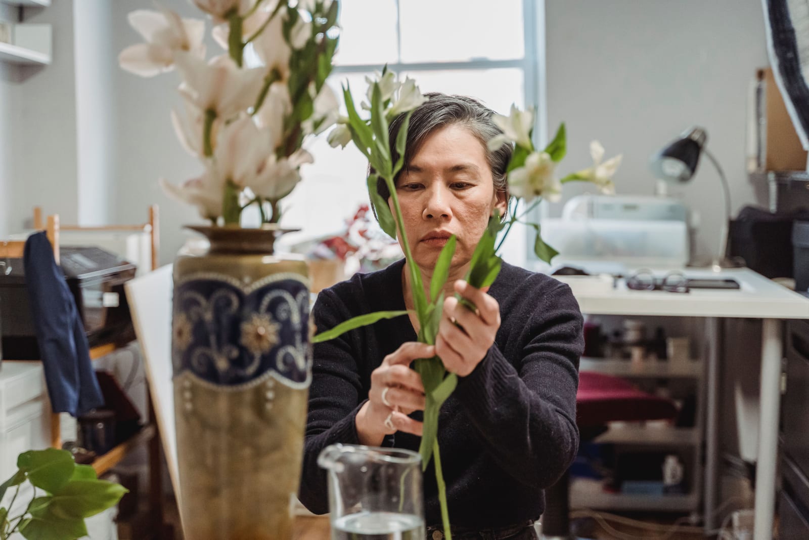 A floral designer arranging tall stems in a studio.